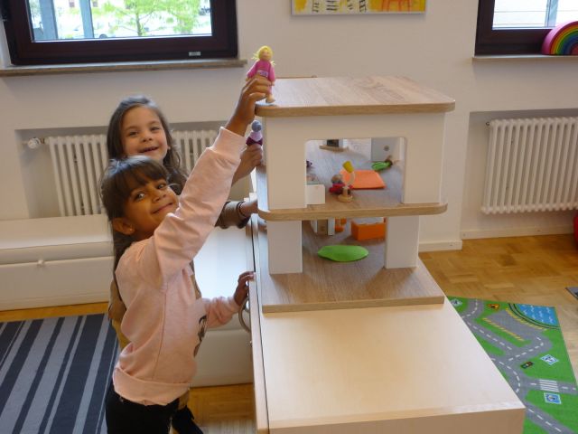 Die Kinder freuen sich über das neue Puppenhaus.